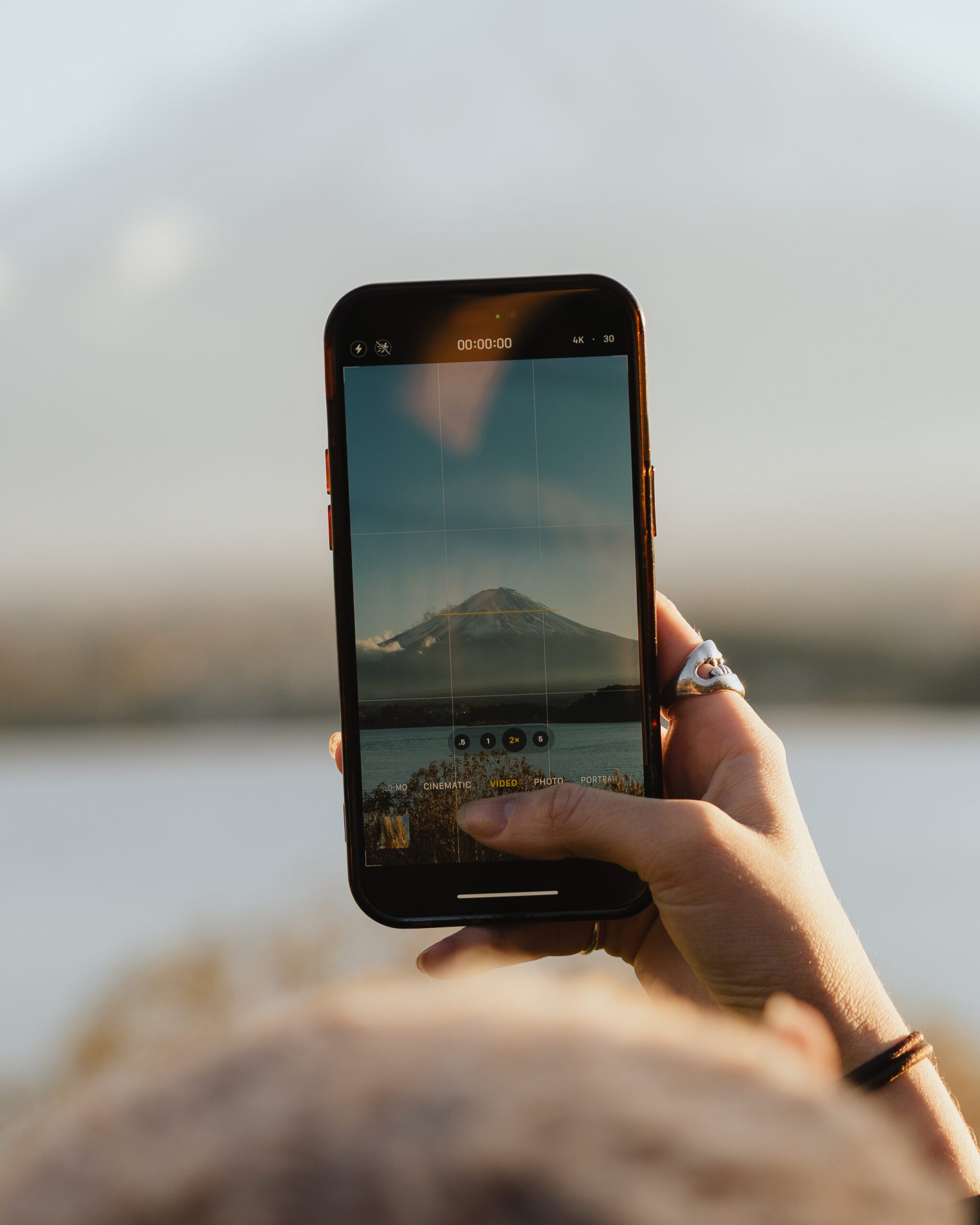 Hand holding an iPhone filming Mount Fuji across Lake Kawaguchiko in Japan using the video camera app. Best SIM card for Japan.