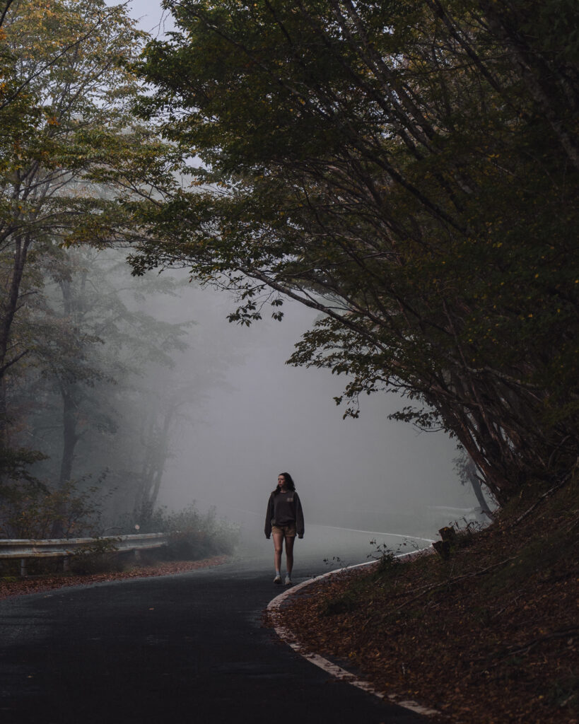 Woman walking along a foggy mountain road in rural Japan surrounded by autumn trees, illustrating the need for eSIM connectivity in remote locations