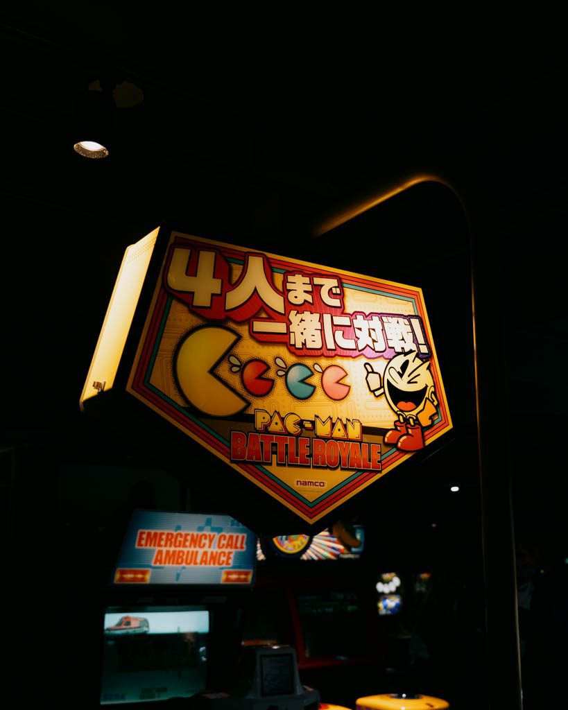 Illuminated arcade game signage hanging inside a multi-storey Akihabara arcade