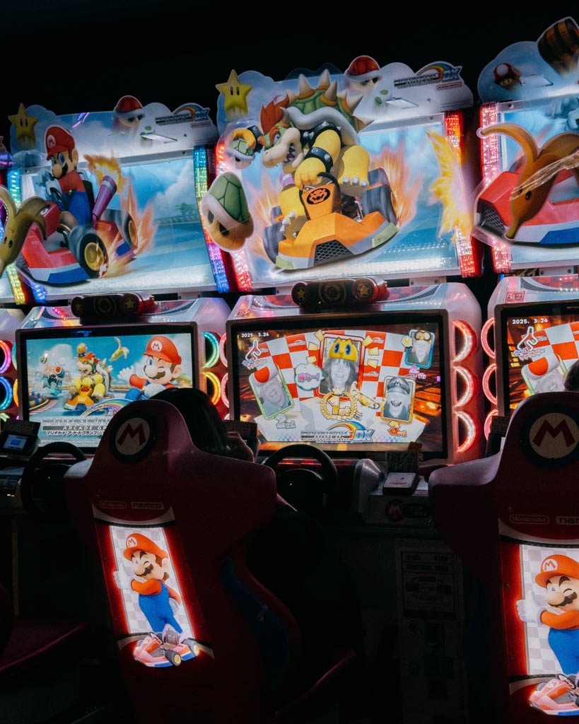 Row of racing arcade machines with lit-up seats inside an Akihabara arcade