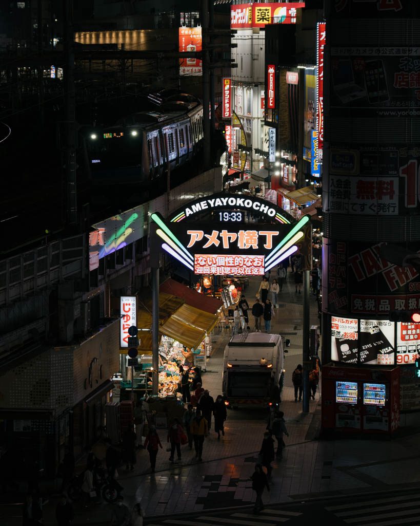 Ameyoko Market entrance sign lit up at night with a train passing on the tracks above