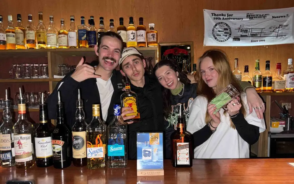 Group of friends working and socialising behind the bar at a whisky bar in Nozawa Onsen, Japan during a ski season