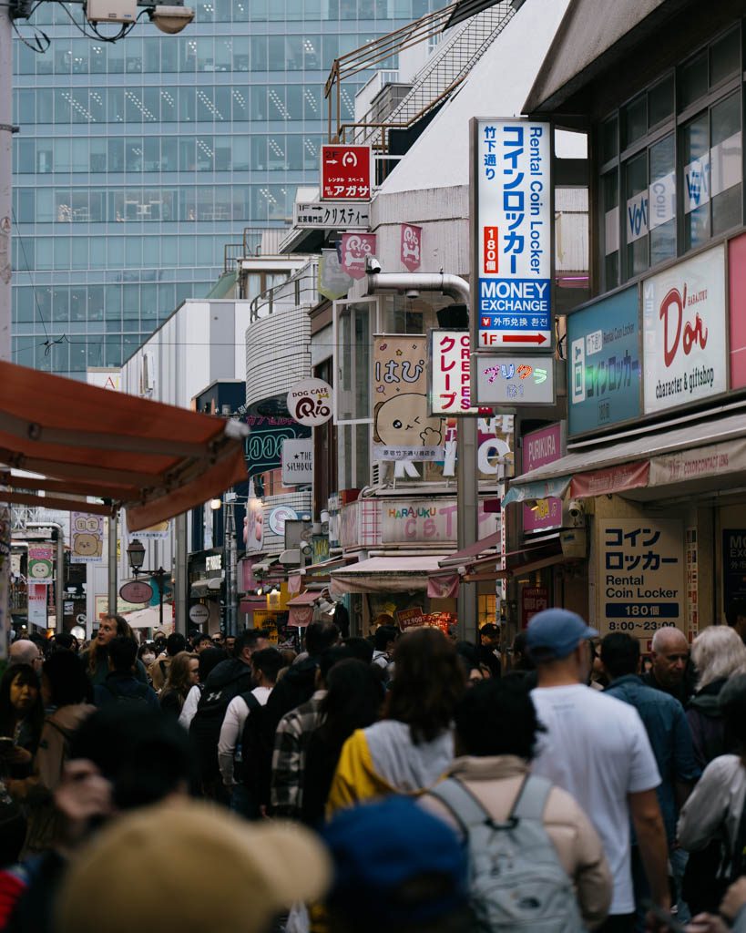 Crowded backstreet near Takeshita Street lined with shops and signage in Harajuku