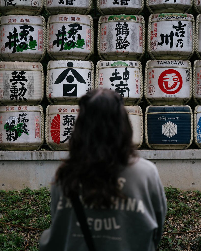 Visitor viewing the decorative sake barrel wall (kazaridaru) at the entrance to Meiji Jingu