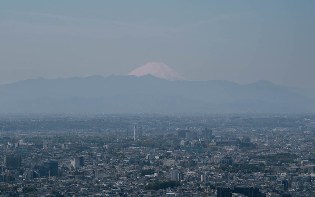 Mount Fuji visible above the Tokyo skyline in daytime haze from Shibuya Sky