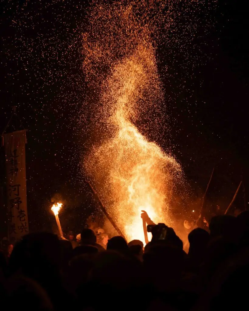 Sparks erupt into the night sky above the crowd during the Nozawa Onsen Dosojin Fire Festival in Nagano, Japan.