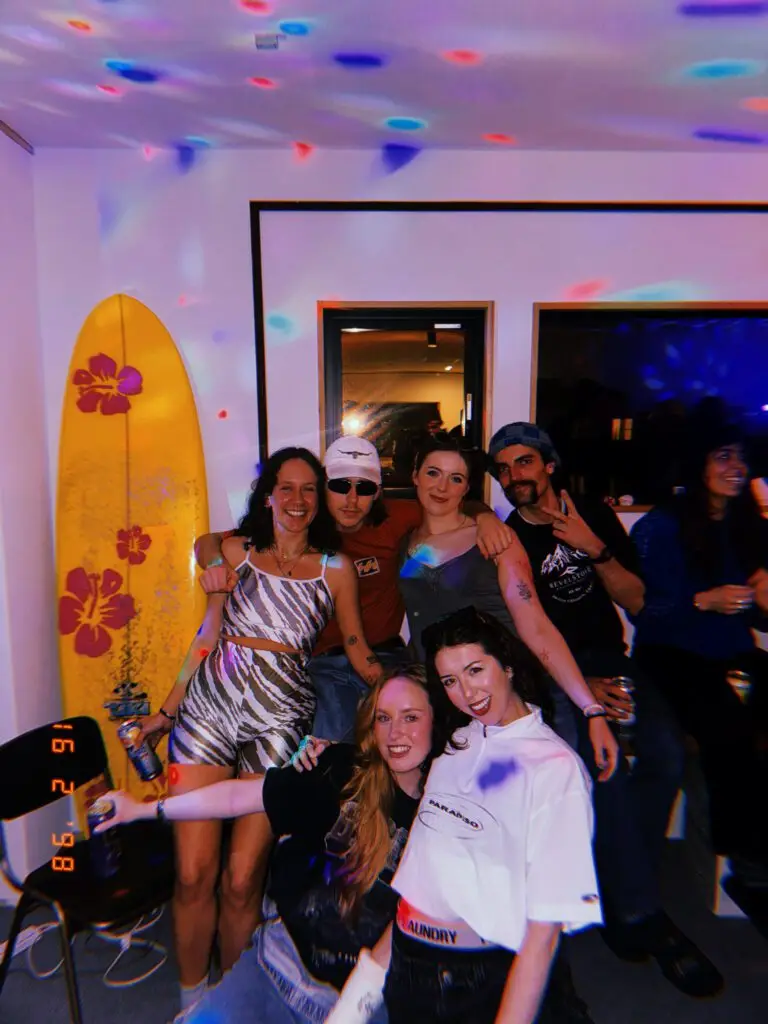 Group of ski season workers at a Nozawa Onsen house party during winter, celebrating after a day on the mountain.