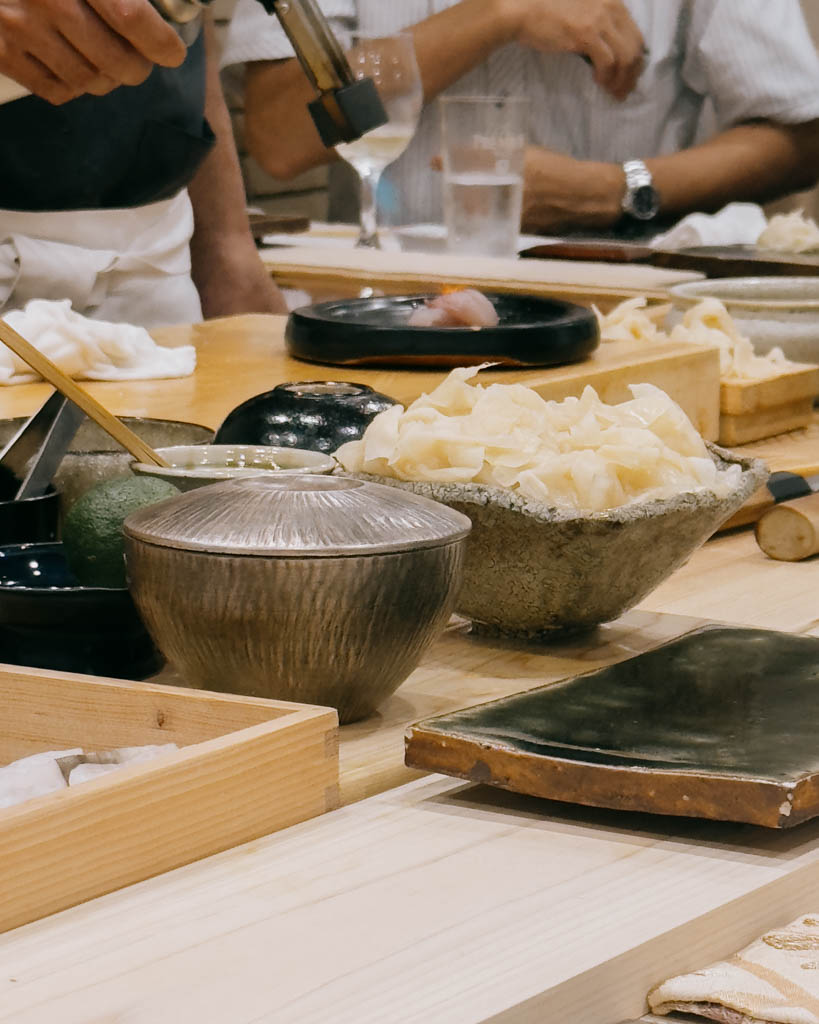 Chef torching a piece of nigiri behind the counter during an omakase dinner in Tokyo