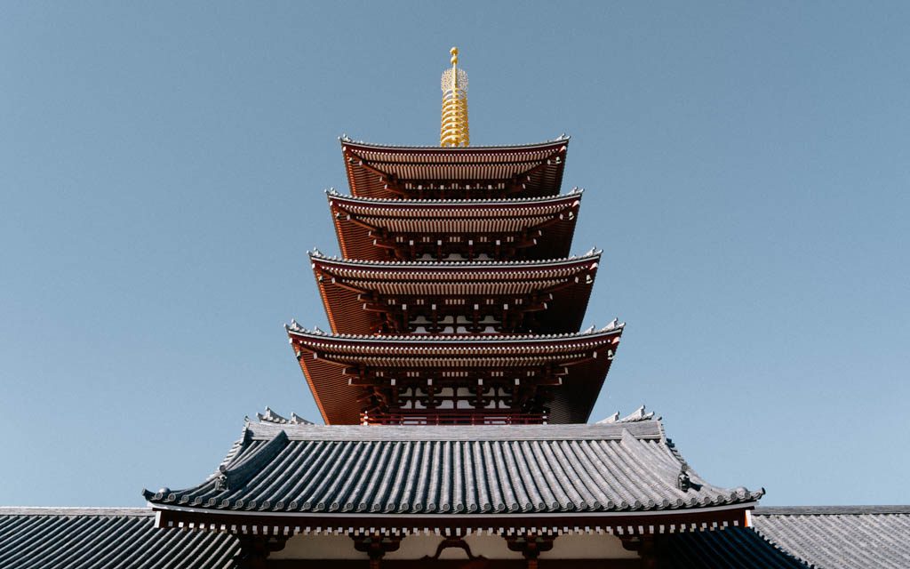 Senso-ji's five-storey pagoda rising above a temple rooftop against a clear blue sky