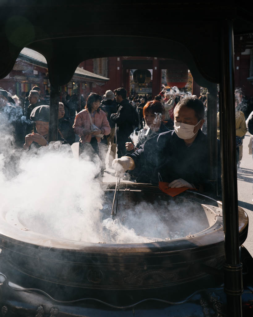 Visitors gathered around the large incense censer at Senso-ji Temple with smoke rising over the crowd