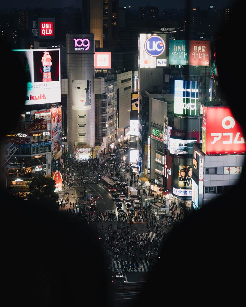 Aerial view of Shibuya Scramble Crossing lit up with neon signage at night