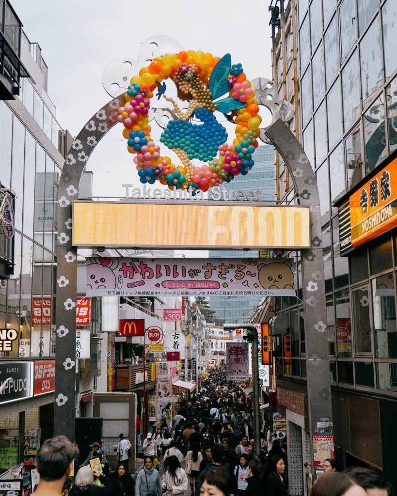 Crowds entering Takeshita Street beneath its decorative arch in Harajuku