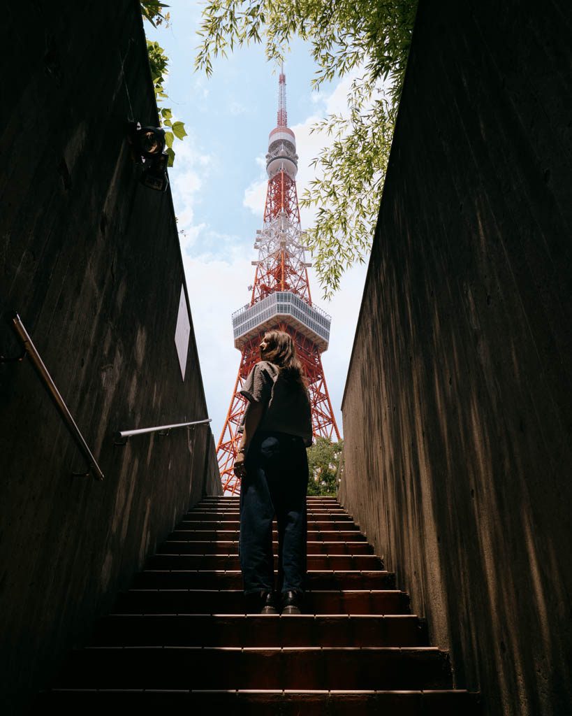 Visitor looking back toward Tokyo Tower from the staircase photo spot in daylight