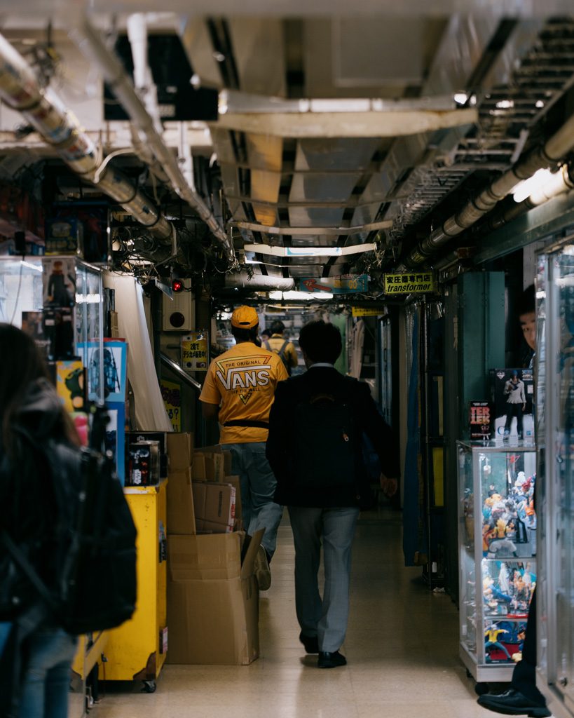 Narrow shop corridor in Akihabara lined with collectible figures and merchandise