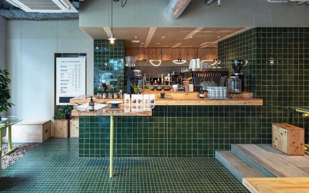 Green tiled coffee counter with espresso machine and menu board inside All Day Place Shibuya
