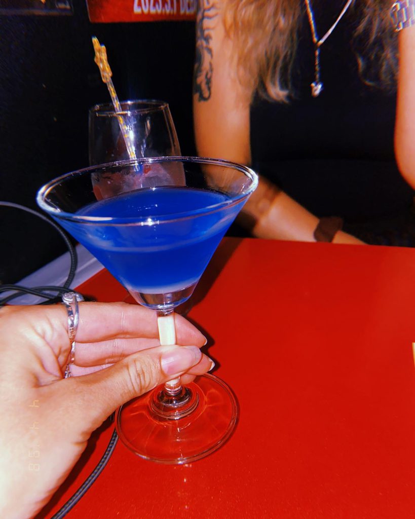 Blue cocktail in a martini glass on a red table at Bar Moonwalk