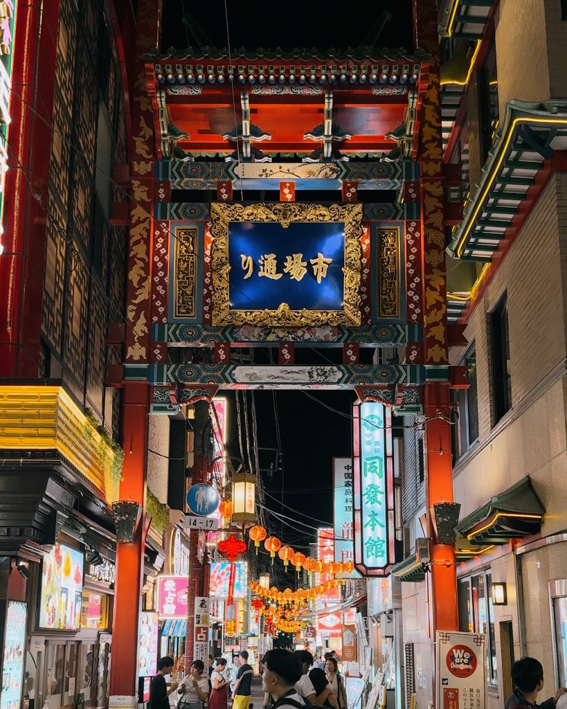 Ornate red and gold gate marking a street entrance into Yokohama Chinatown at night