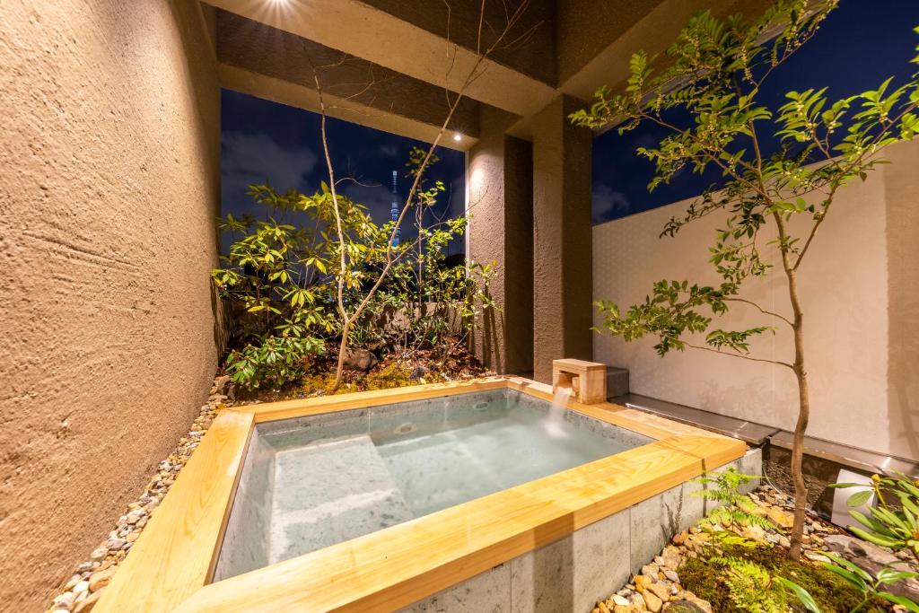 Private open-air bath at Cyashitsu Ryokan Asakusa surrounded by greenery with Tokyo Skytree visible at night