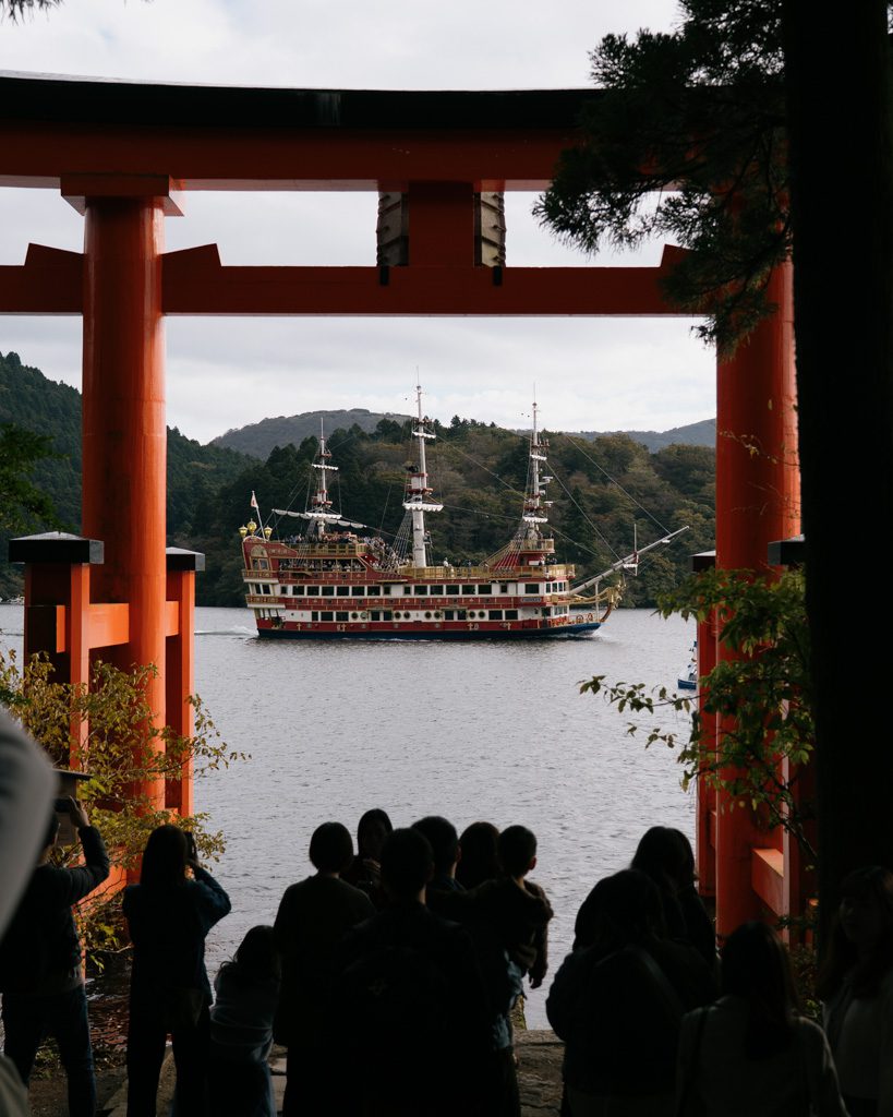 Lake Ashi pirate ship cruise viewed through the red torii gate at Hakone Shrine