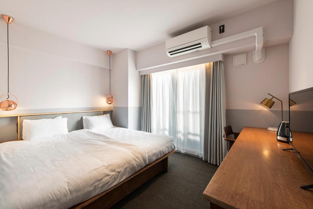 Guest room at Hotel Asakusa KANNONURA with a double bed, work desk, and copper pendant lighting