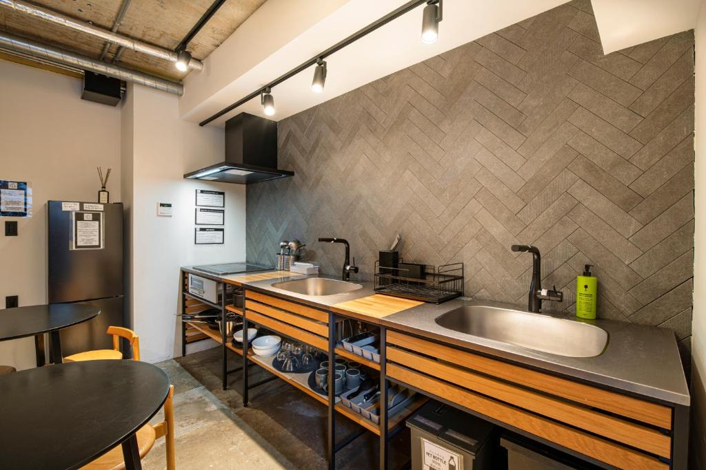 Shared kitchen at Hotel Asakusa KANNONURA with dual sinks, herringbone tile splashback, and dining tables