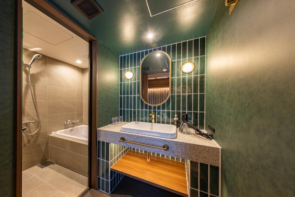 Stylish green-tiled bathroom at Hotel Keihan Asakusa with a bathtub, walk-in shower, and vanity sink