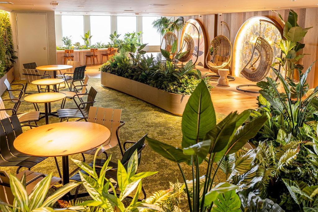 Indoor lounge with hanging rattan chairs surrounded by lush greenery