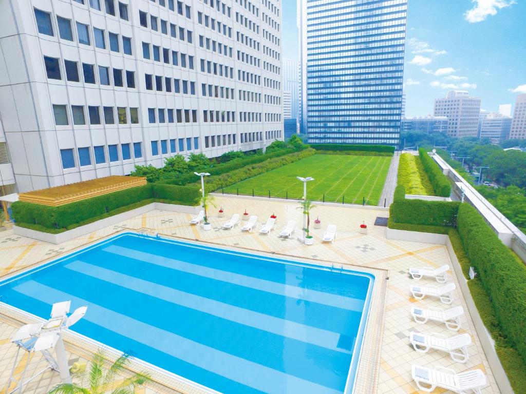 Outdoor rooftop pool surrounded by loungers with a Tokyo high-rise backdrop