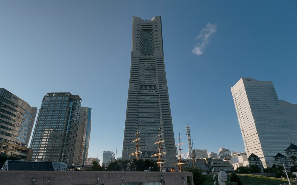 Landmark Tower rising above Yokohama's skyline, with the Nippon Maru's masts visible in the foreground