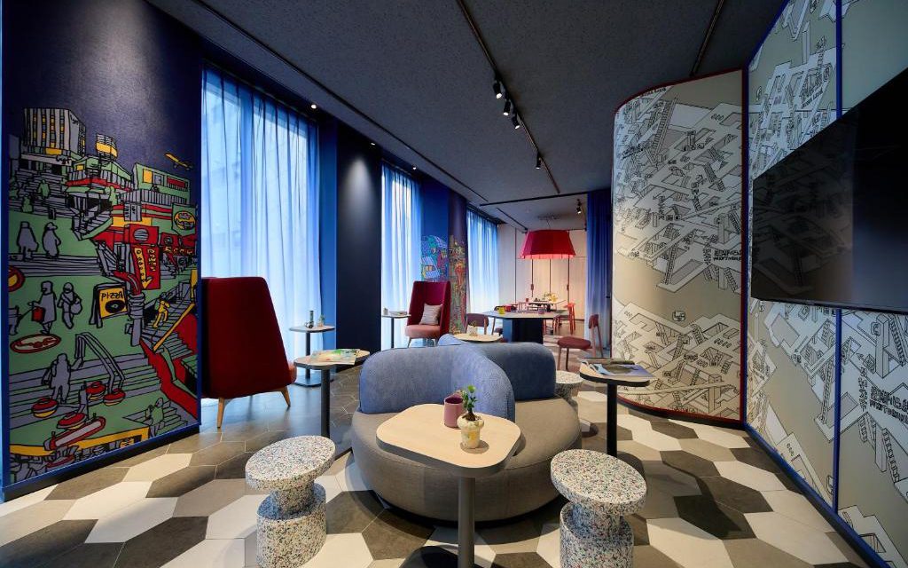 Colourful communal lounge with patterned tile floor, mural wall, and shared seating