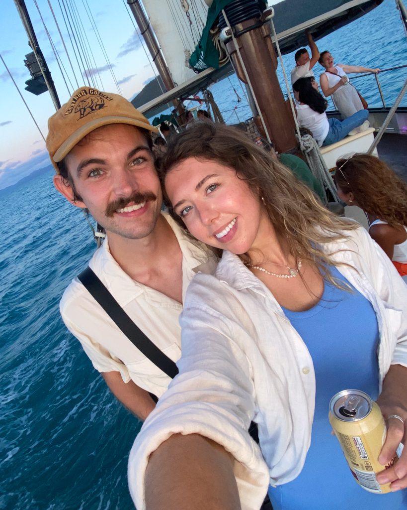 Mark and Sarah taking a selfie on a sailing boat in the Whitsundays at sunset