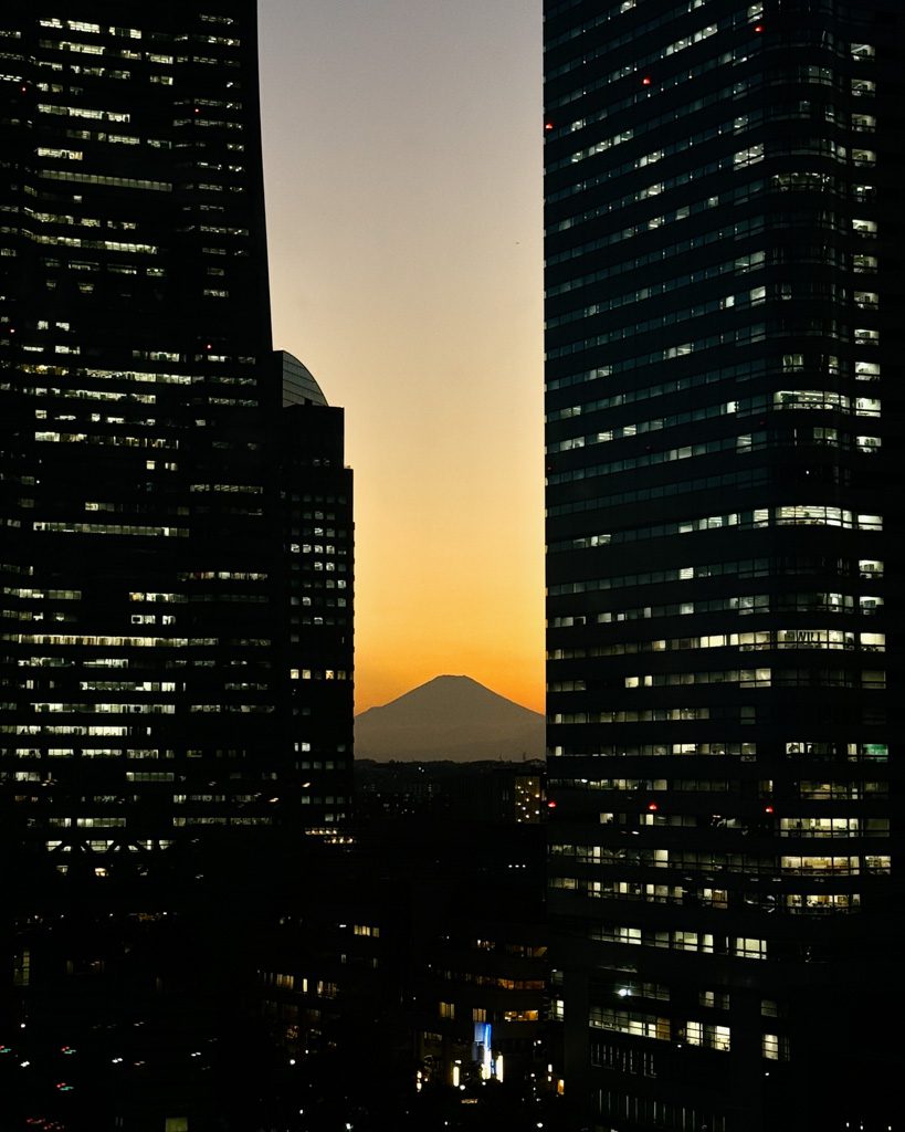 Mount Fuji silhouette at sunset framed between Yokohama skyscrapers, seen from the ferris wheel
