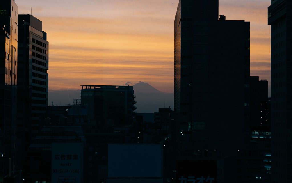 Mount Fuji silhouetted at sunset behind the Shibuya skyline