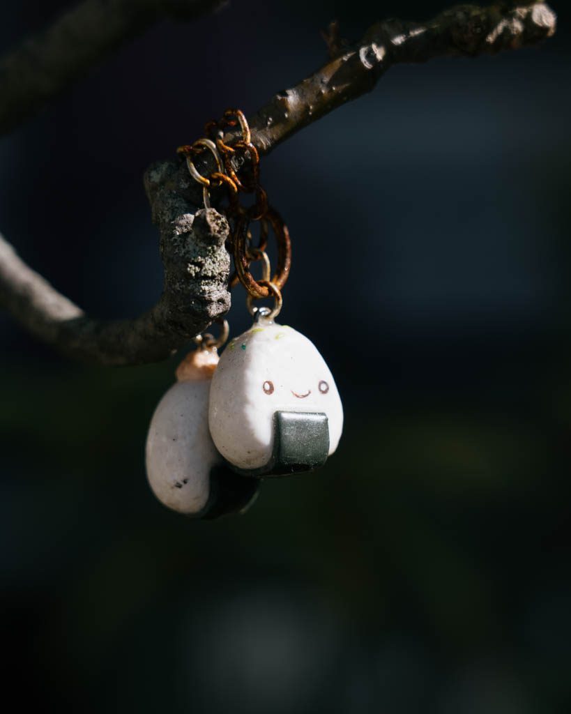 Close-up of a smiling onigiri-shaped charm hanging from a tree branch