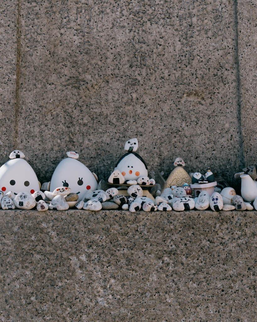 Row of painted onigiri-shaped stone figures at a small shrine in Asakusa