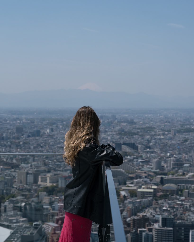 Woman looking out over the Tokyo skyline with Mount Fuji visible in the distance