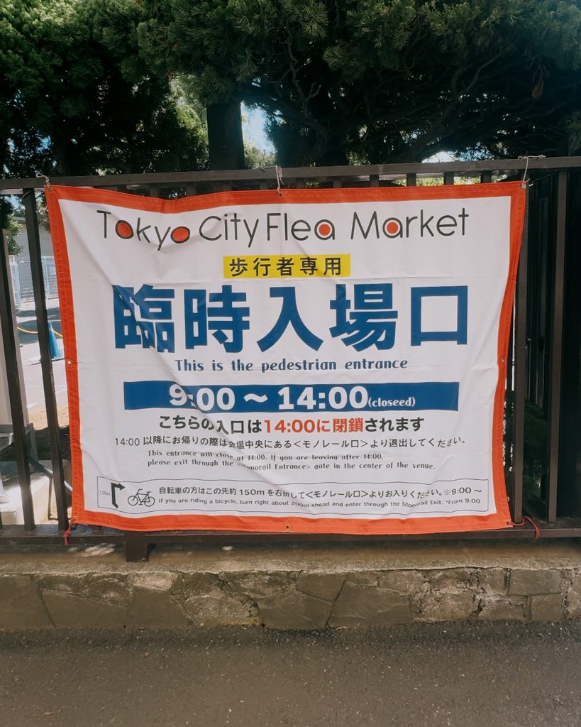 Tokyo City Flea Market pedestrian entrance sign showing opening hours at Oi Racecourse