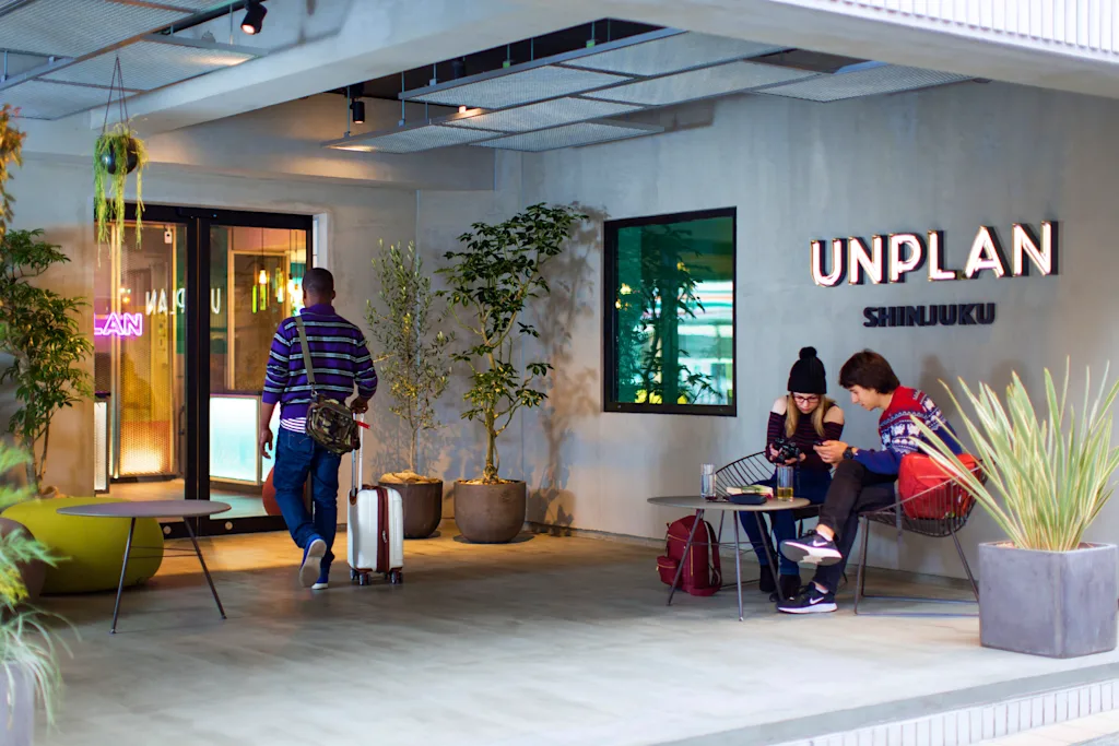 Guests relaxing near the entrance sign at Unplan Shinjuku hostel