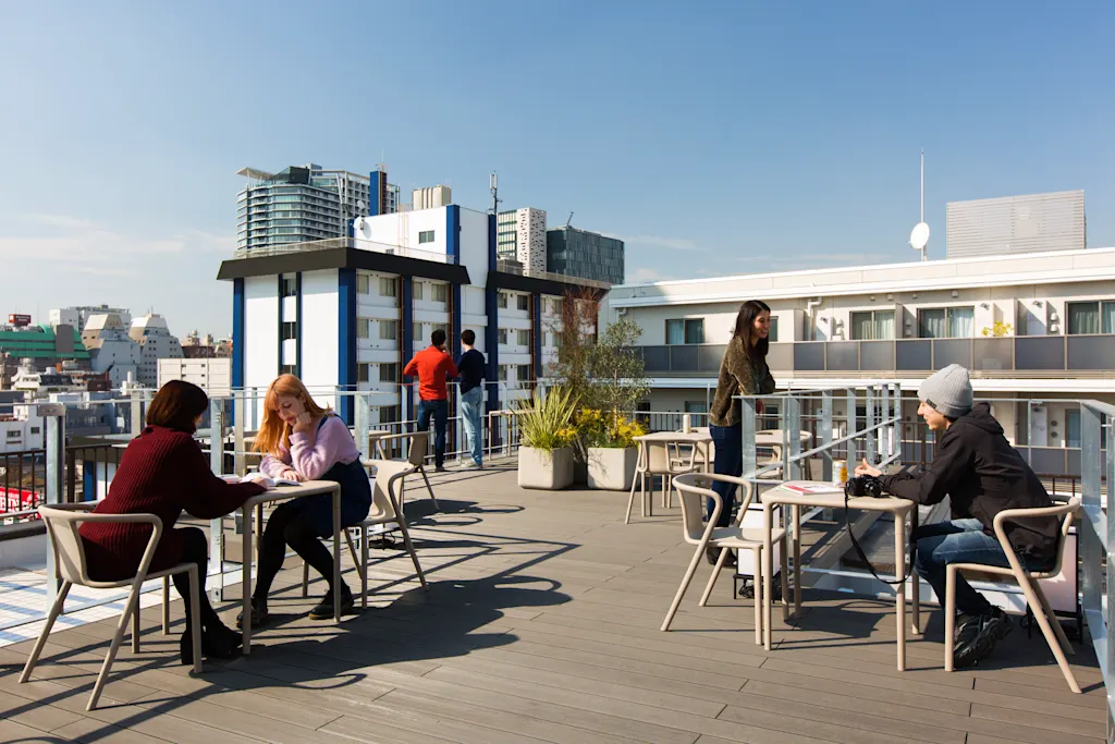 Guests sitting at outdoor tables on the rooftop terrace at Unplan Shinjuku hostel