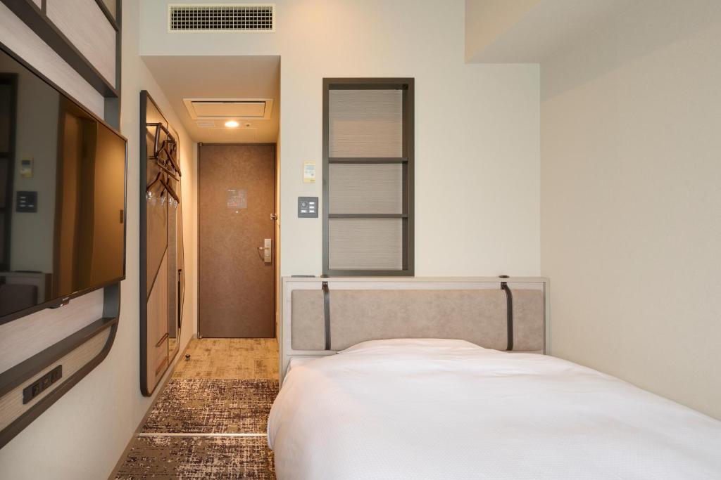 Small hotel room at Via Inn Shinjuku with wall-mounted TV and entryway storage