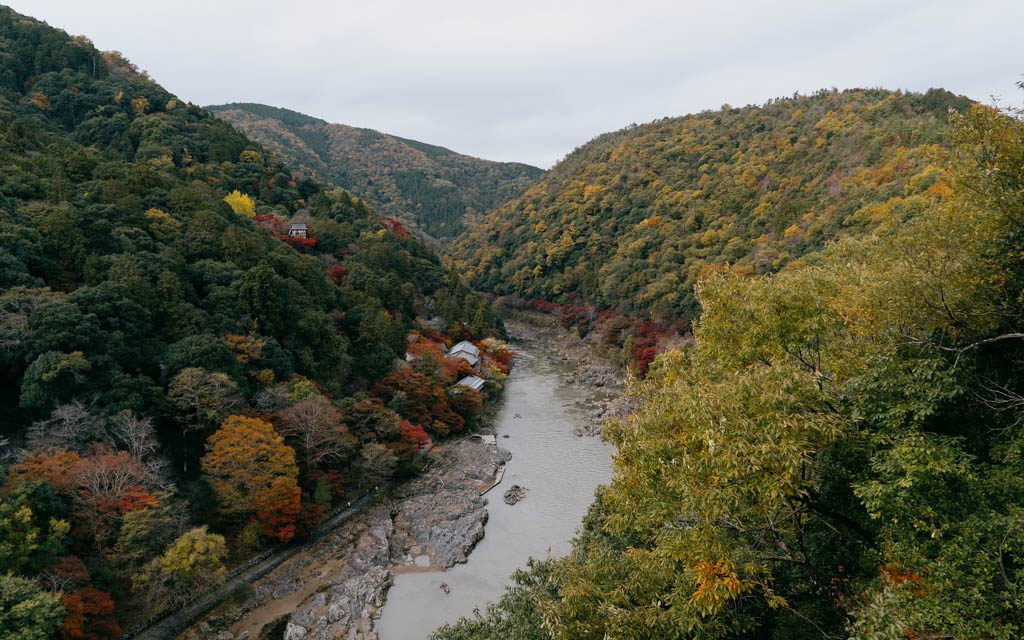 Wide view of the river gorge at Arashiyama surrounded by autumn-coloured hillsides