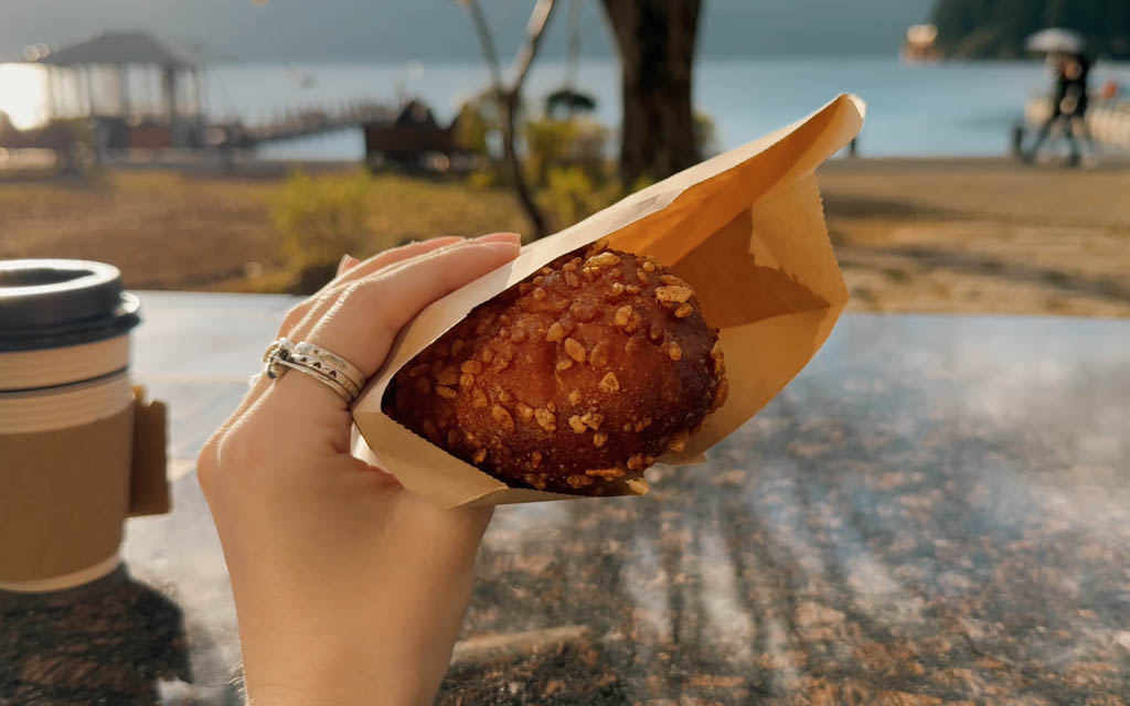 Freshly bought curry pan from Bakery & Table with Lake Ashi in the background