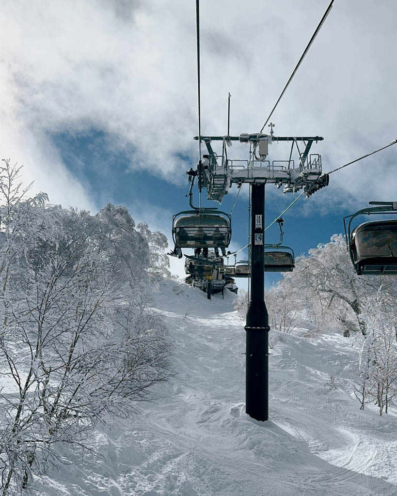 Chairlift climbing through snow-covered trees towards the summit of Nozawa Onsen for backcountry gate access