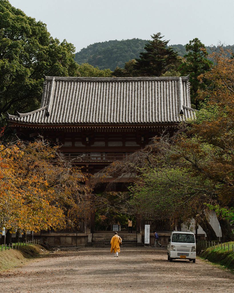 Monk walking towards the Niomon gate at Daigo-ji surrounded by autumn trees