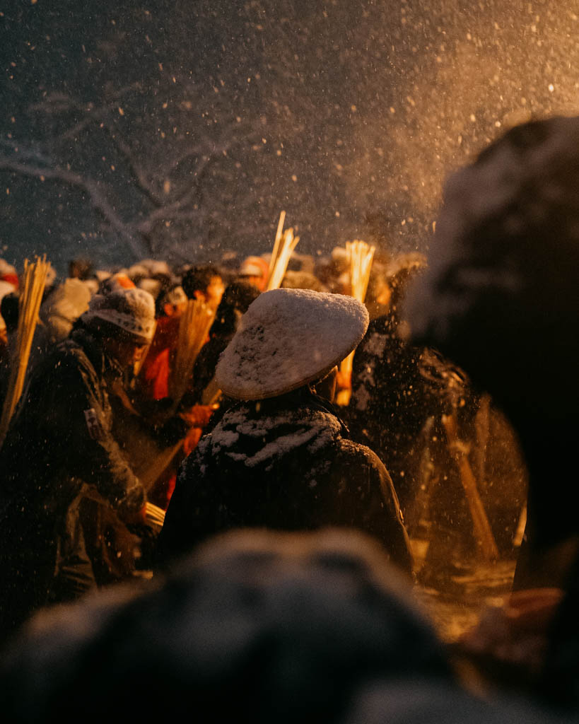 Villagers holding flaming torches around the decorated shaden at night during the Dosojin Fire Festival in Nozawa Onsen
