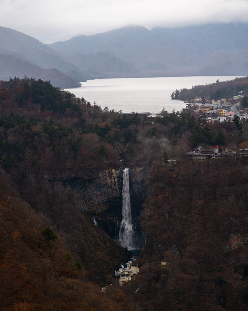 Kegon Falls dropping into a gorge with Lake Chuzenji and mountains in the background, seen from Akechidaira