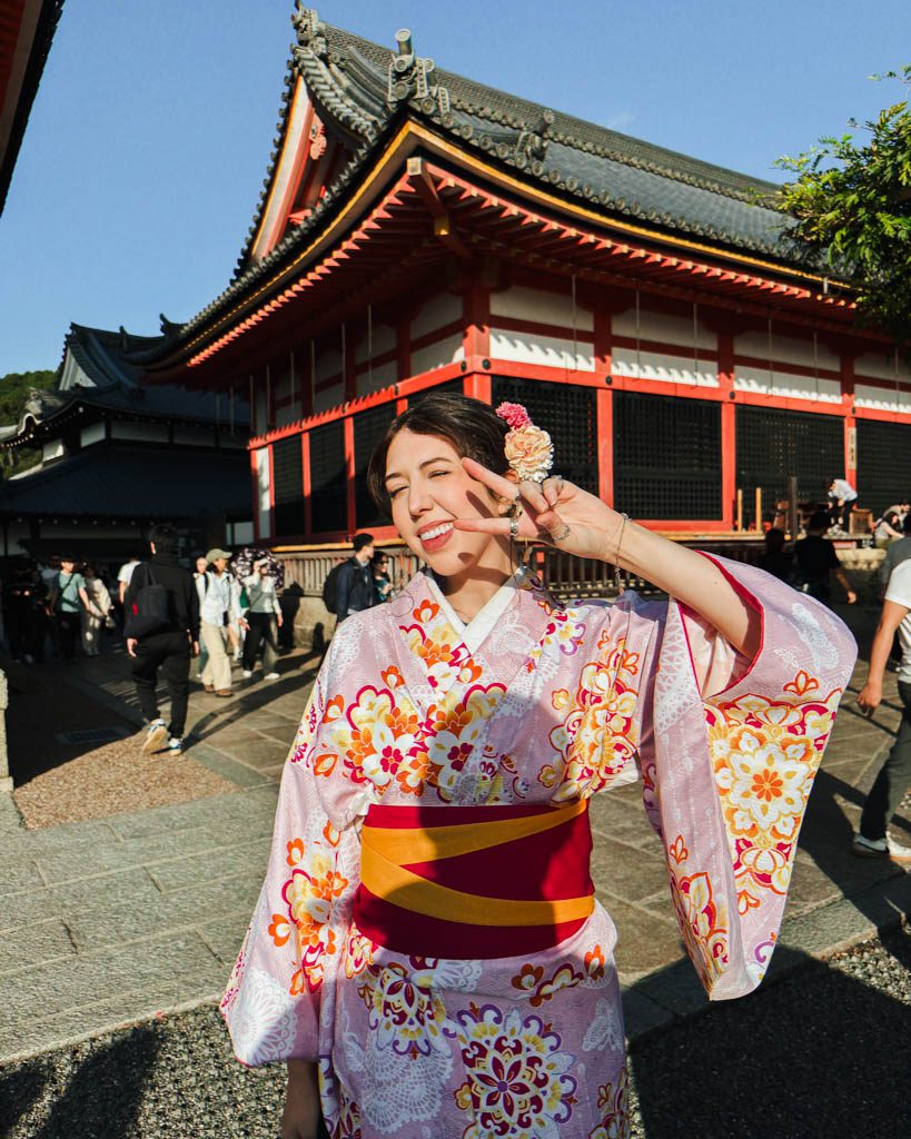 Woman wearing a pink floral kimono in front of the main hall at Kiyomizu-dera
