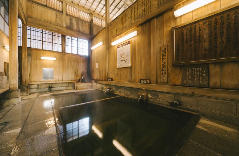 Interior of a traditional wooden public onsen bath house in Nozawa Onsen with steaming hot spring water