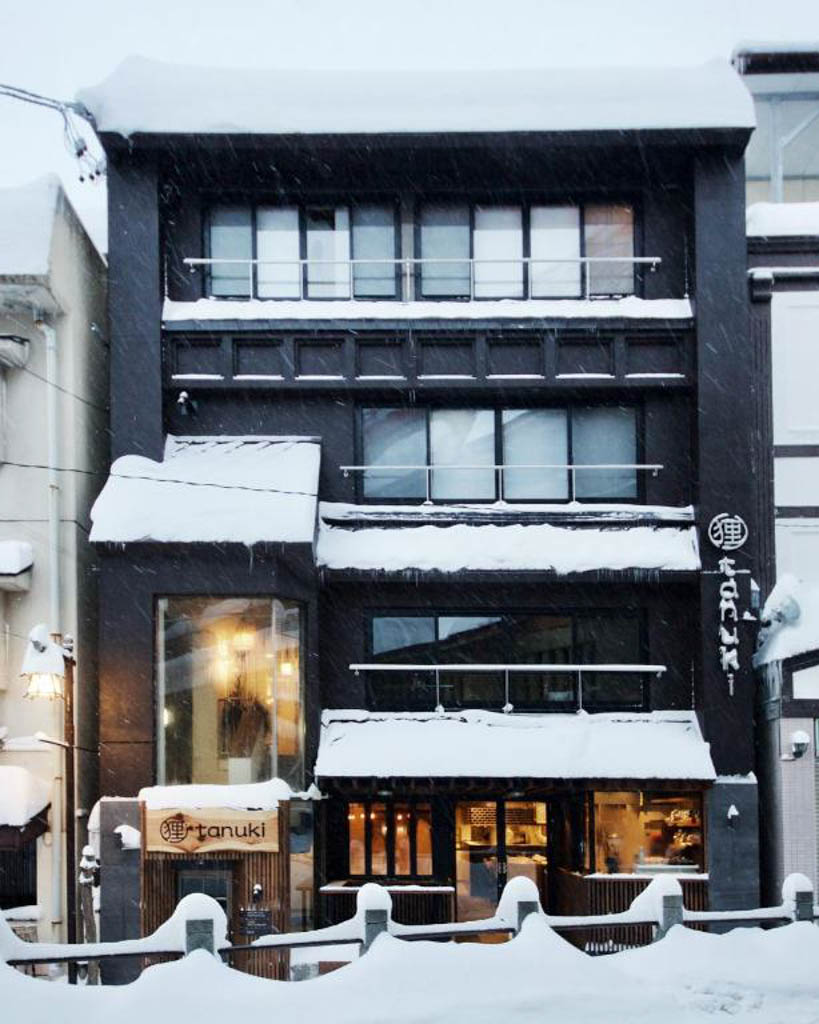Snow-covered exterior of Tanuki Nozawa hotel at night