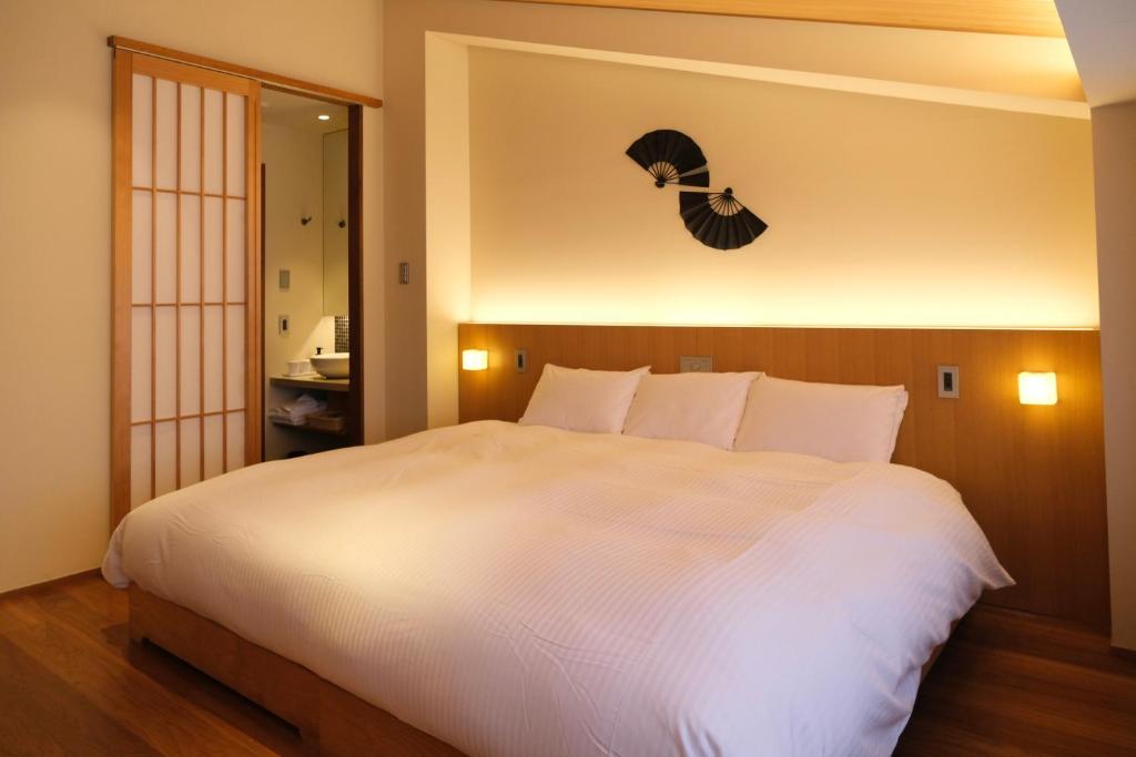 Hotel bedroom with a large bed, wall-mounted fan decoration, bedside lamps, and a shoji sliding door to the bathroom